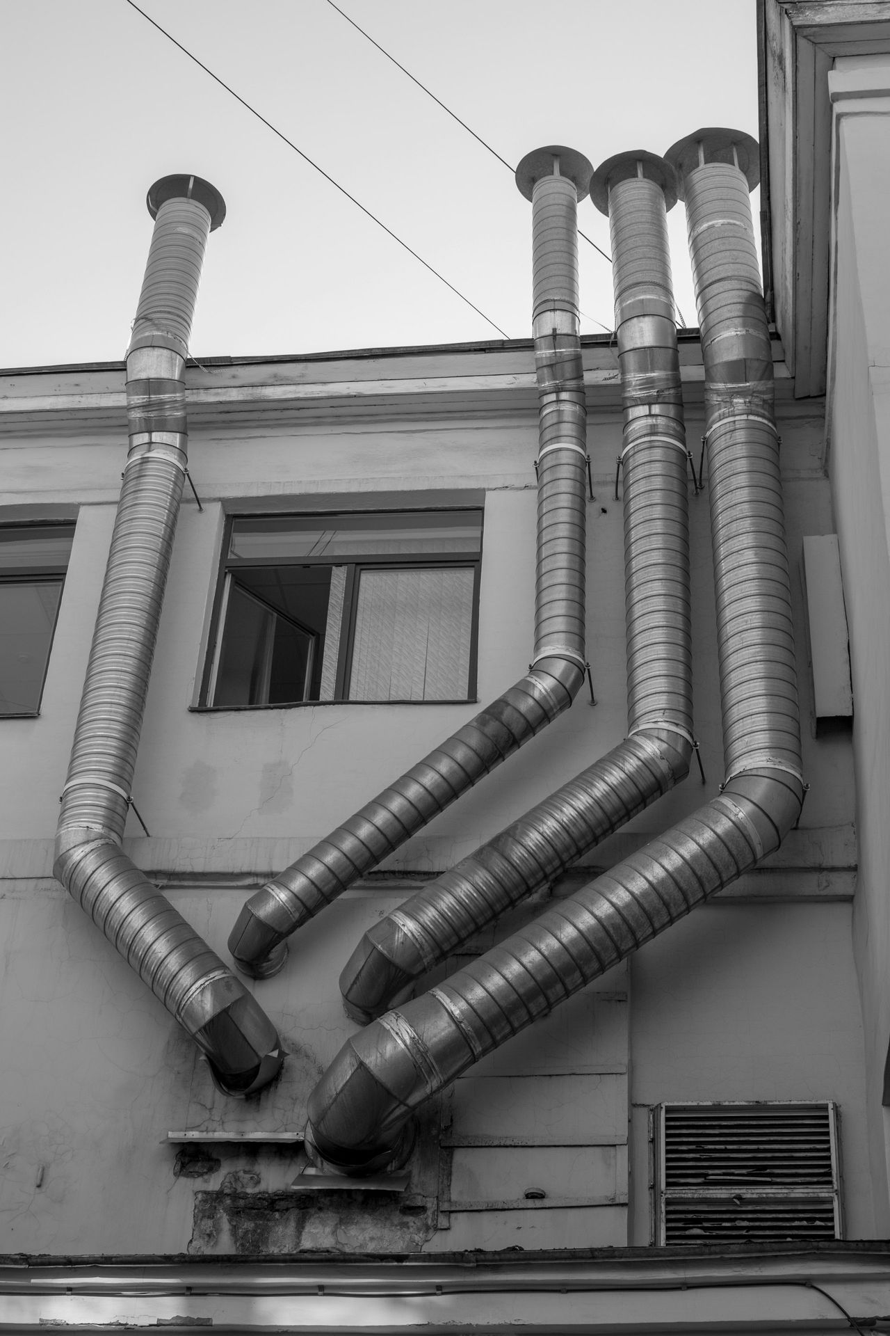 a black and white photo of a building with a bunch of pipes attached to it